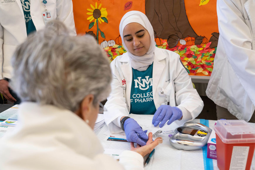 A pharmacy student practices with a patient.