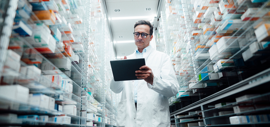 pharmacist with tablet standing in shelves