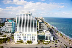 Aerial view of a beachfront city with high-rise buildings and a long sandy beach.