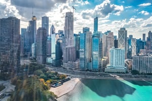 Aerial view of a city skyline with tall buildings along a waterfront on a sunny day.
