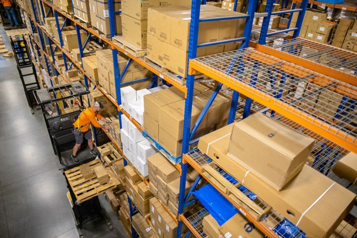 <span>Forklift order picker in a third-party logistics warehouse, surrounded by storage shelves neatly stacked with boxes. </span>