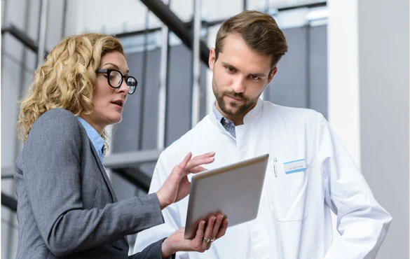 A hospital administrator shows a doctor something on a tablet<br>